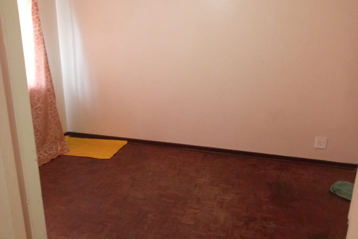 An empty bedroom featuring parquet flooring and neutral walls, offering a blank canvas for potential renovation or interior design updates.