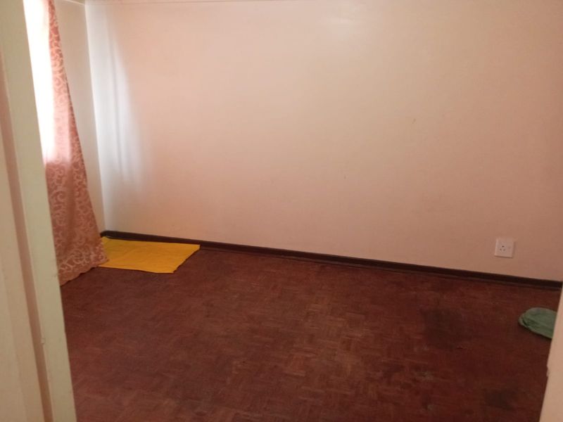 An empty bedroom featuring parquet flooring and neutral walls, offering a blank canvas for potential renovation or interior design updates.