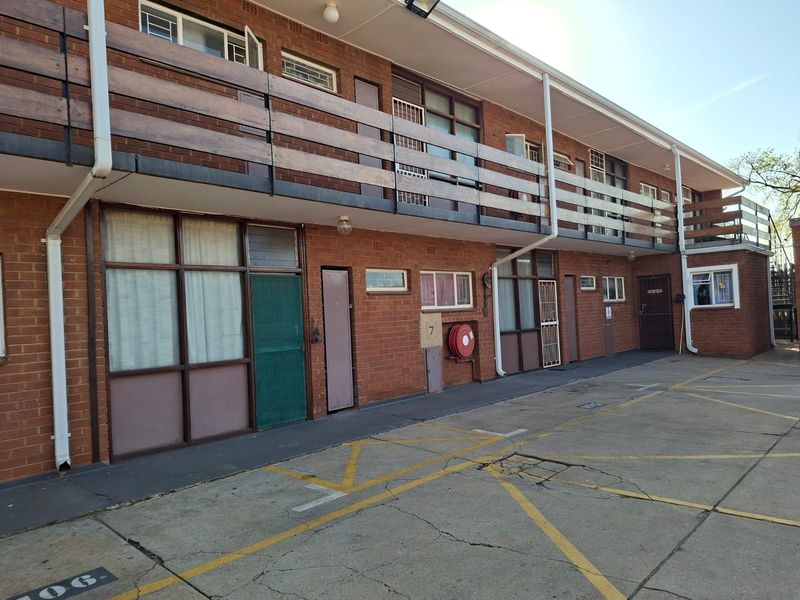 Exterior view of a multi-story apartment complex featuring brick facade, balcony access, and dedicated paved parking area.