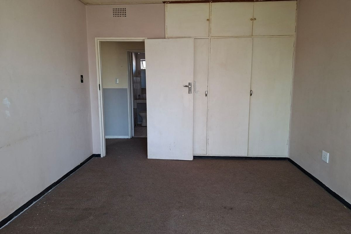 An empty bedroom featuring built-in cupboards and carpeted flooring, requiring cosmetic updates to improve its overall condition and appeal.