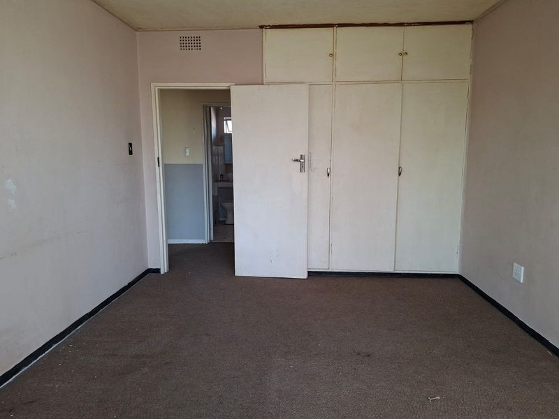 An empty bedroom featuring built-in cupboards and carpeted flooring, requiring cosmetic updates to improve its overall condition and appeal.
