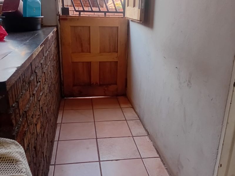 A functional scullery area featuring a brick-based counter, tiled flooring, and a stable-style door leading to the exterior.