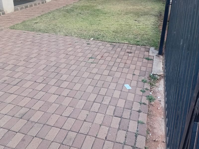 A private rear garden area featuring a paved patio, a small lawn, and secure perimeter fencing.