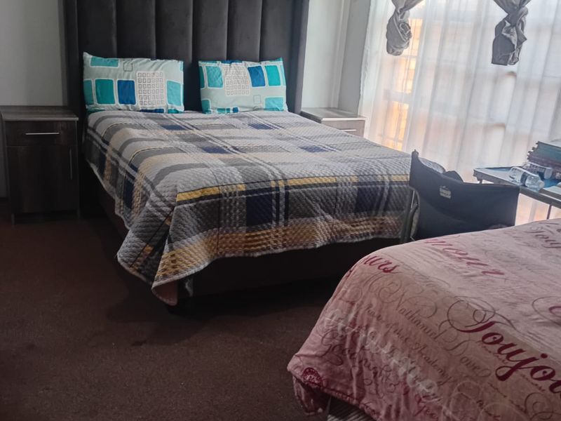 A functional bedroom featuring carpeted flooring, curtain rails, and a wall-mounted electrical distribution board.