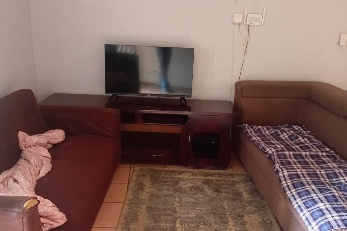A compact living room area featuring tiled flooring and visible wall imperfections, offering a functional space ready for cosmetic updates and modernization.