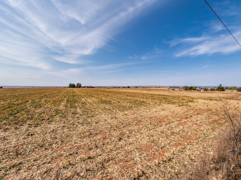 A wide-angle view of expansive, flat residential vacant land under a clear blue sky, suitable for development.
