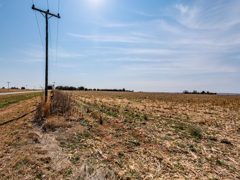 A view of a vacant residential plot featuring open land and an adjacent utility pole with overhead power lines.