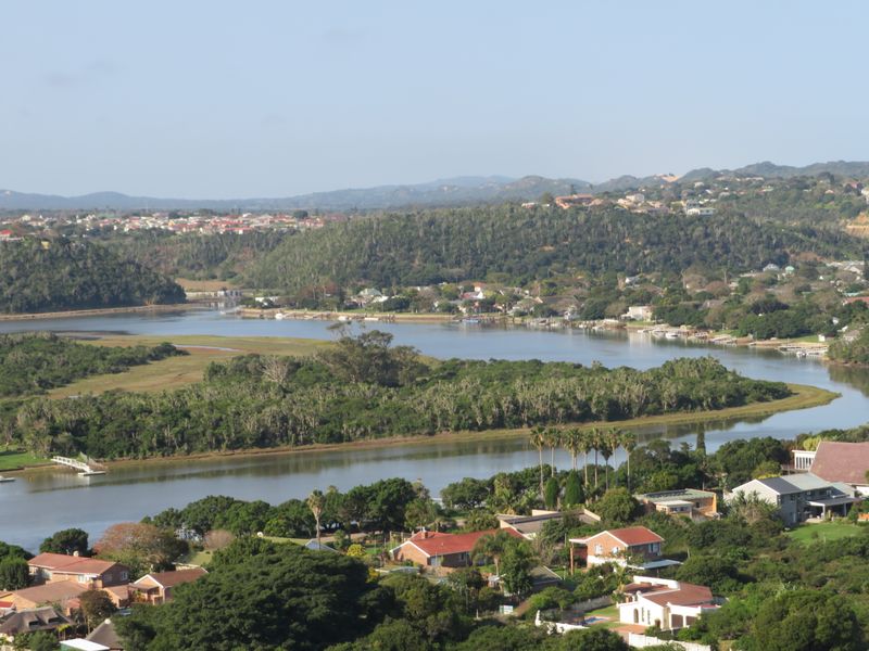 A scenic elevated view overlooking a river, lush coastal vegetation, and surrounding residential properties.
