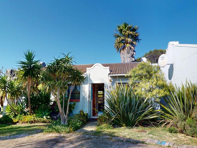 Front elevation of a townhouse featuring a tiled roof, paved driveway, and established garden landscaping.