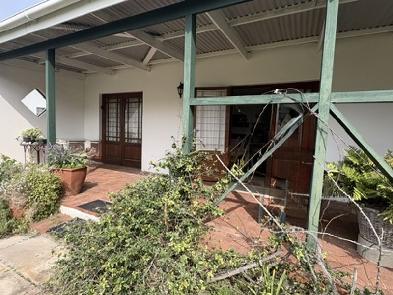 A covered patio area featuring terracotta tiling, timber support beams, and direct access to the interior through timber-framed glass doors.