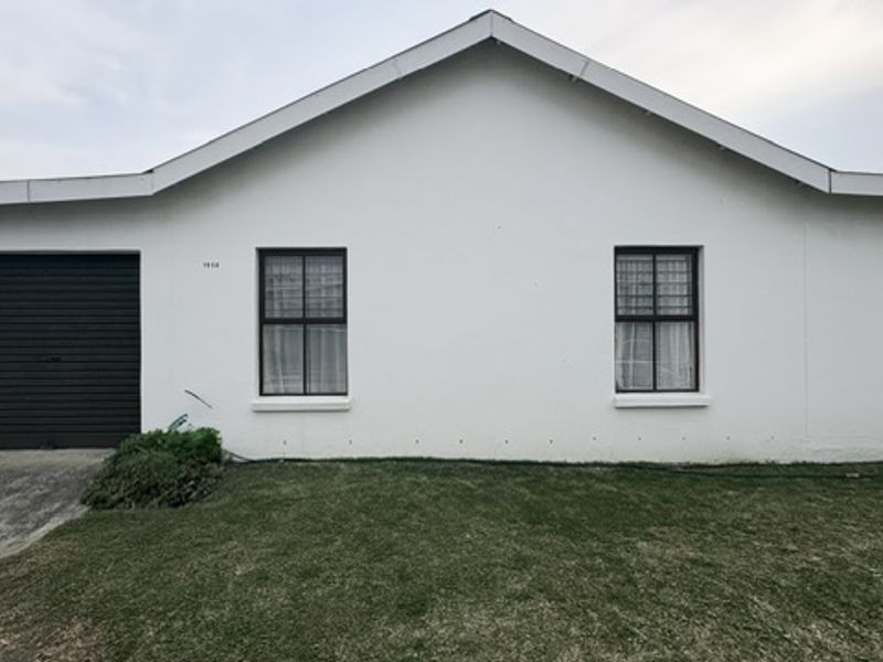 Front elevation of a single-story house featuring a garage, white rendered facade, and a mix of rectangular and diamond-shaped windows.