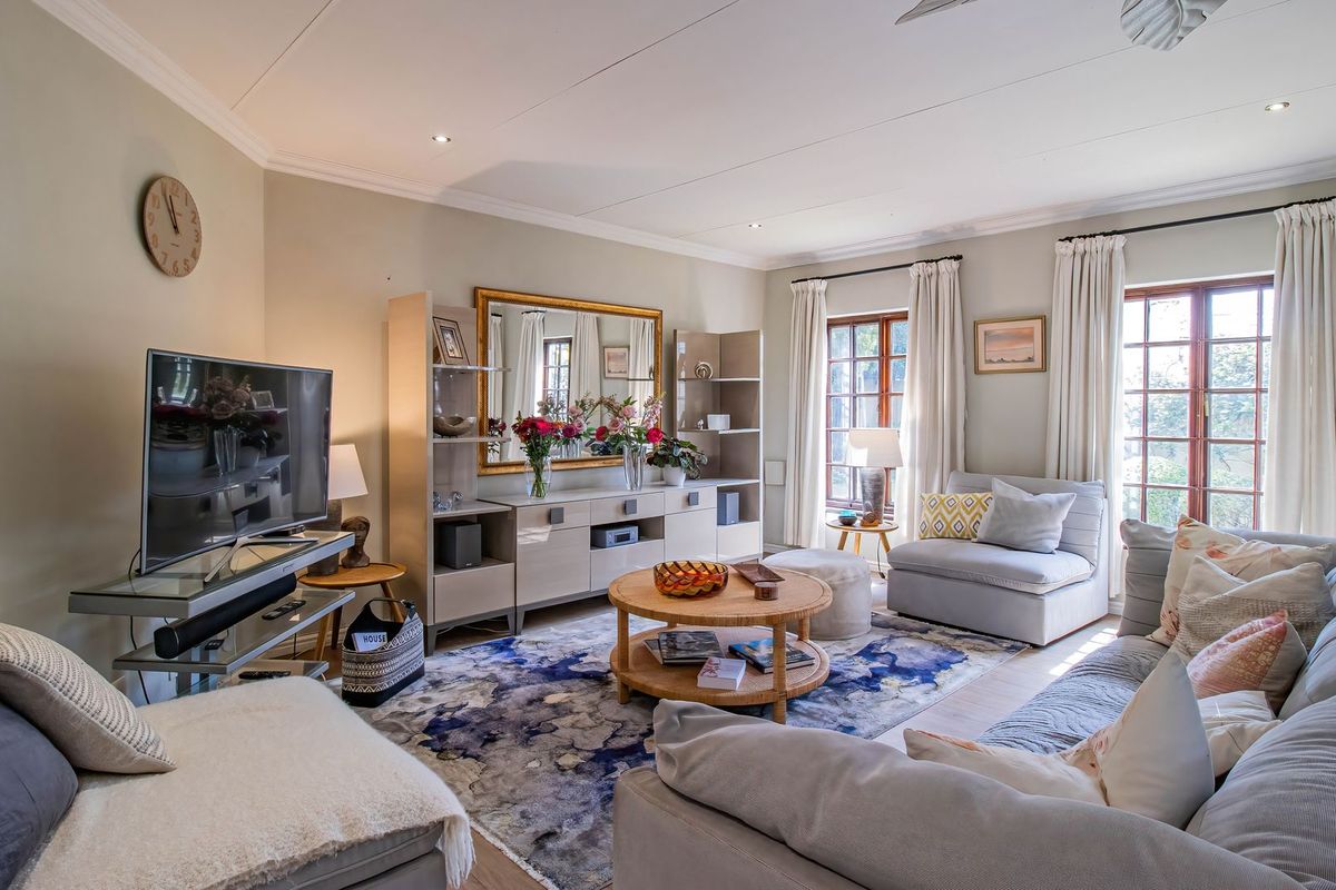 A well-maintained living room featuring recessed downlighting, timber-framed windows, and neutral wall finishes, creating a comfortable and inviting atmosphere.