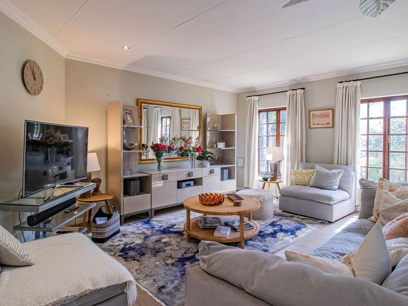 A well-maintained living room featuring recessed downlighting, timber-framed windows, and neutral wall finishes, creating a comfortable and inviting atmosphere.