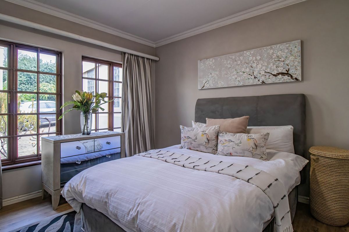 A well-maintained bedroom featuring timber-framed windows, crown molding, and laminate flooring, offering a comfortable and inviting living space.