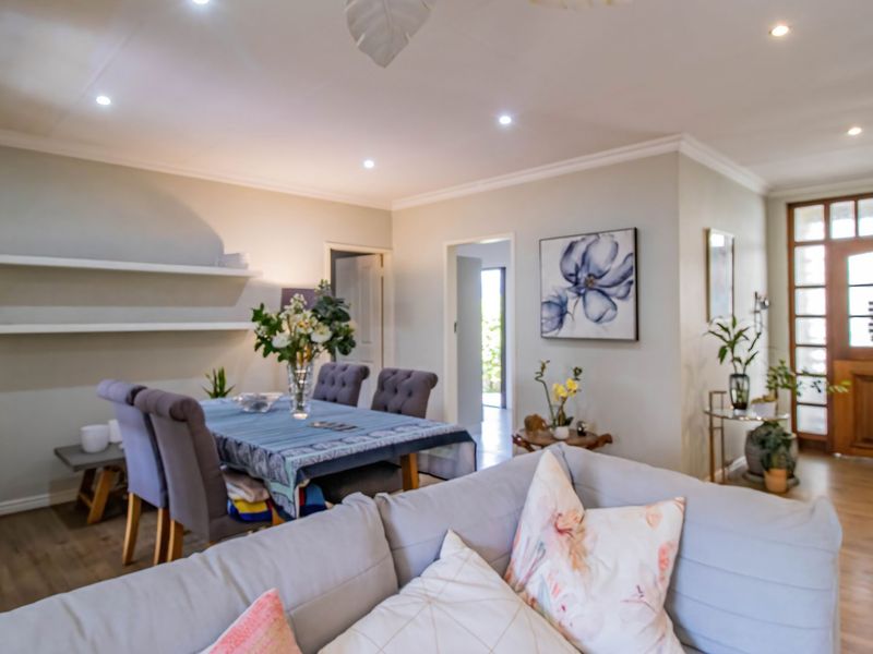 Spacious open-plan living and dining area featuring laminate flooring, recessed downlights, and a classic timber entrance door with glass detailing.