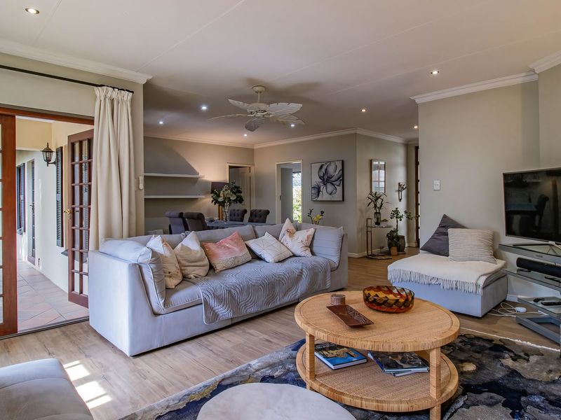 Spacious open-plan living area featuring laminate flooring, recessed lighting, and direct access to an outdoor patio through classic french doors.