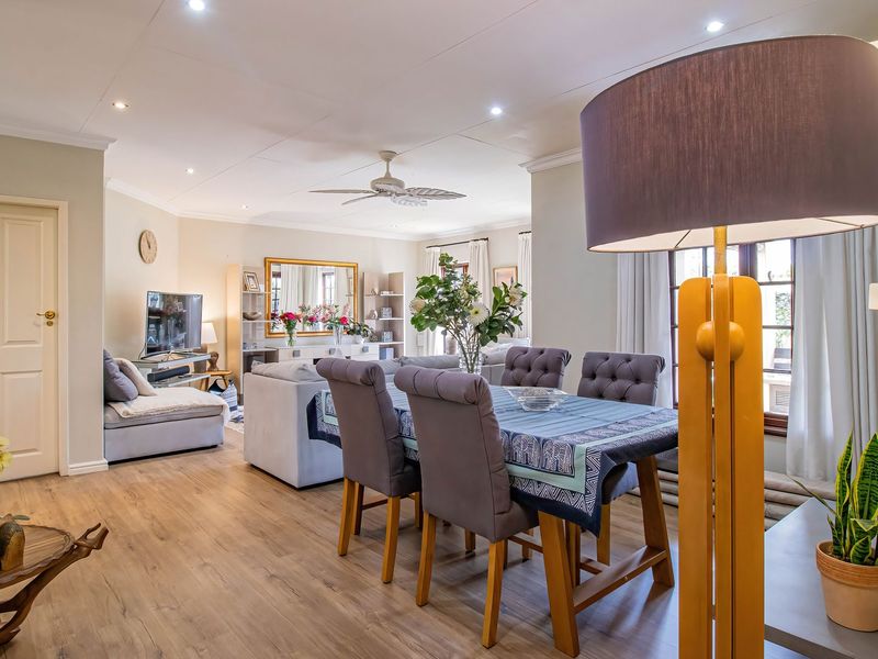 Spacious open-plan living and dining area featuring laminate flooring, recessed downlighting, and a ceiling fan, creating a bright and functional family space.