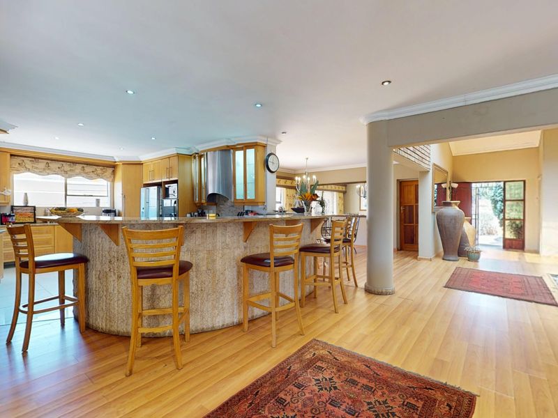 Spacious open-plan kitchen featuring a large stone-clad island, laminate flooring, and integrated cabinetry, flowing into the adjacent living and dining areas.