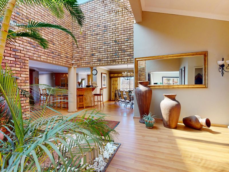 Spacious open-plan living area featuring exposed brick walls, high ceilings with a skylight, and warm laminate flooring, creating a bright and inviting atmosphere.