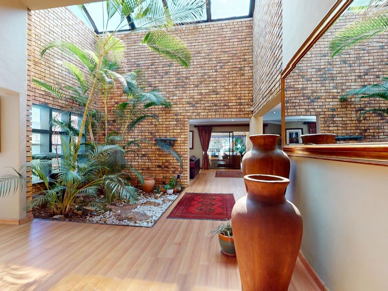Spacious entrance hall featuring a dramatic skylight, exposed brick walls, and a dedicated indoor garden area with laminate flooring.