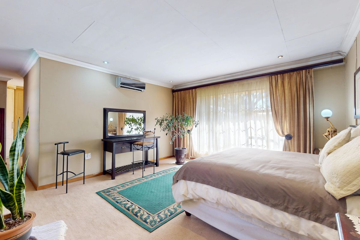 Spacious bedroom featuring neutral walls, recessed lighting, an air conditioning unit, and large windows with curtains.