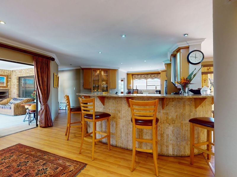 Open-plan living area featuring a stone-clad breakfast bar, laminate flooring, and seamless transition to an adjoining covered patio through sliding glass doors.