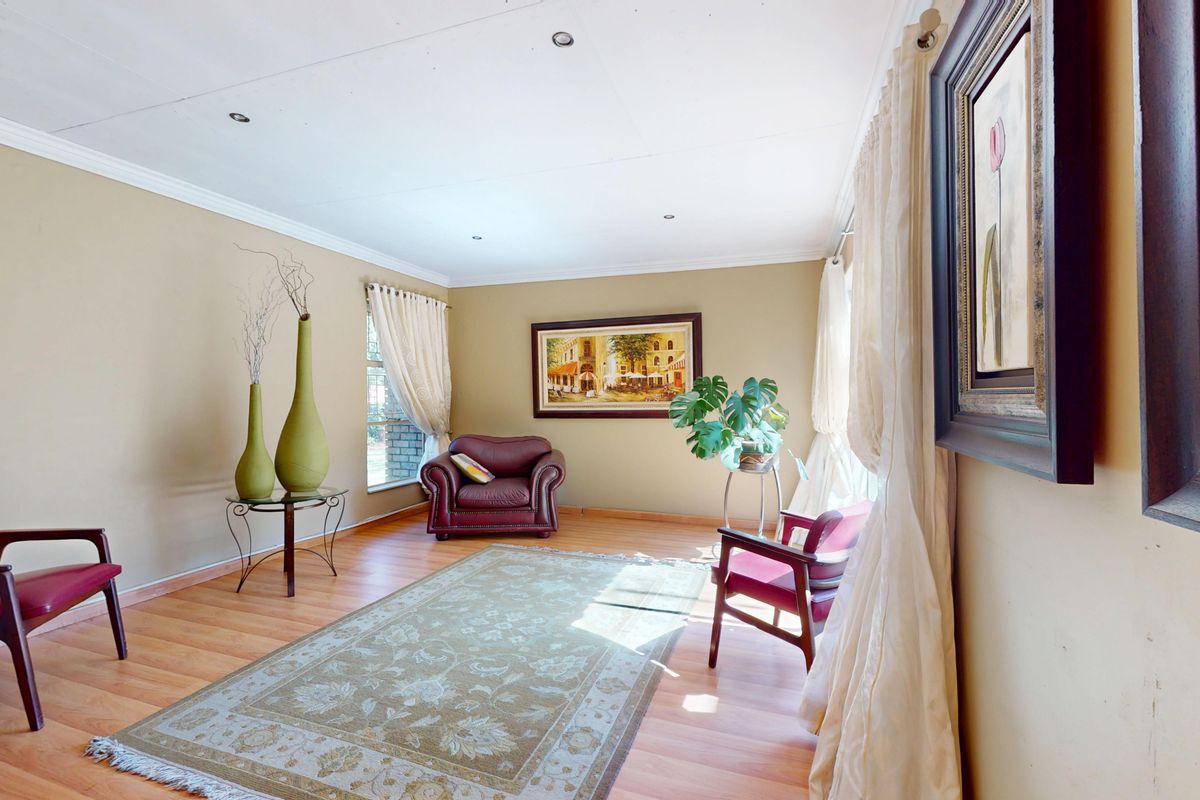 A spacious living room featuring laminate flooring, coved cornicing, and recessed ceiling lighting, offering a comfortable and well-lit area for relaxation.