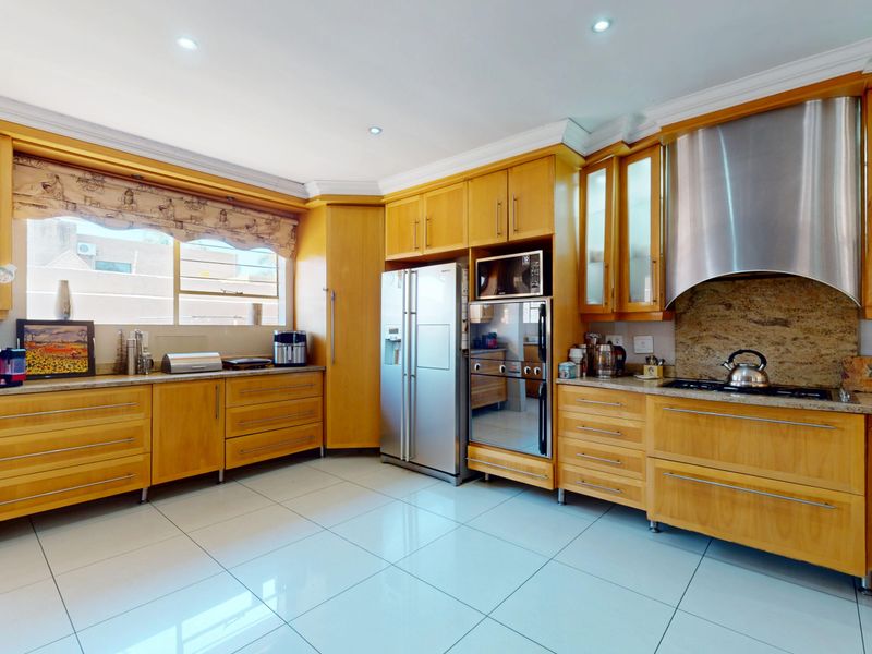 A well-maintained kitchen featuring warm wooden cabinetry, granite countertops, integrated stainless steel appliances, and polished tiled flooring with recessed lighting.