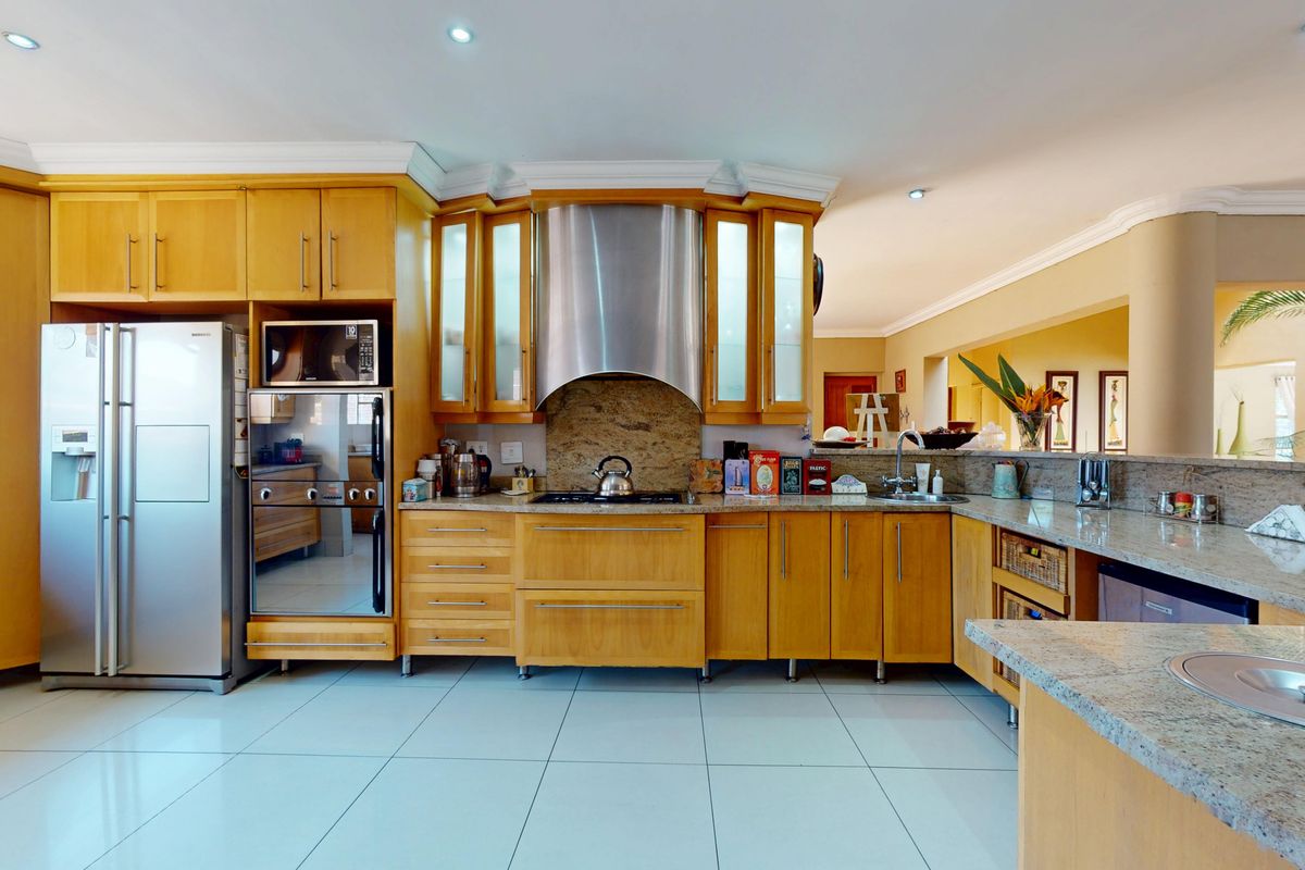 A well-appointed kitchen featuring warm wooden cabinetry, granite countertops, stainless steel appliances, and recessed lighting, offering a functional and classic culinary space.