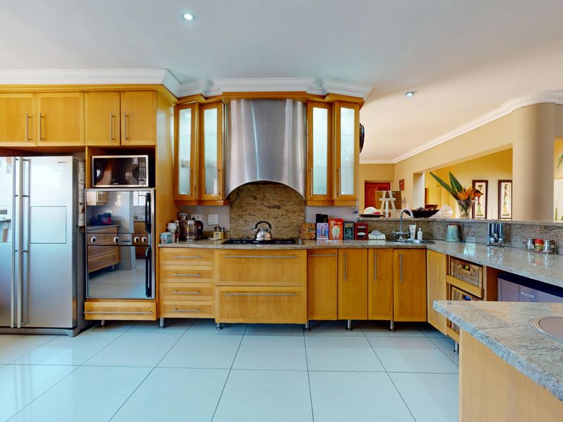 A well-appointed kitchen featuring warm wooden cabinetry, granite countertops, stainless steel appliances, and recessed lighting, offering a functional and classic culinary space.