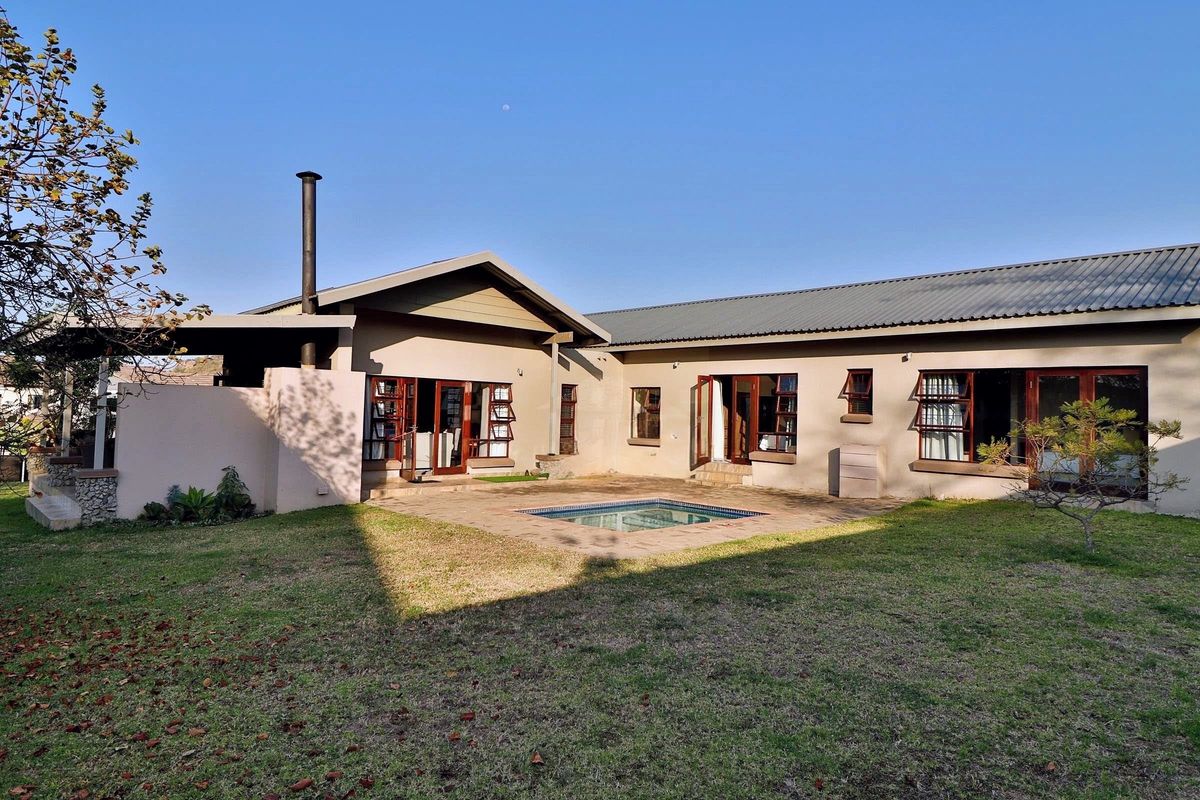 Rear view of the property featuring a paved patio area, a small swimming pool, and direct access to the home through multiple timber-framed doors.