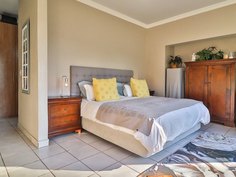 A spacious bedroom featuring neutral walls, tiled flooring, and a built-in wardrobe, offering a functional layout with ample space.