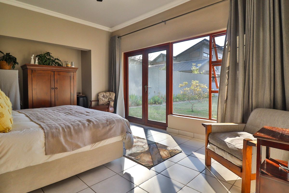 Spacious bedroom featuring tiled flooring, a recessed wall niche, and large glass doors providing direct access to the garden.