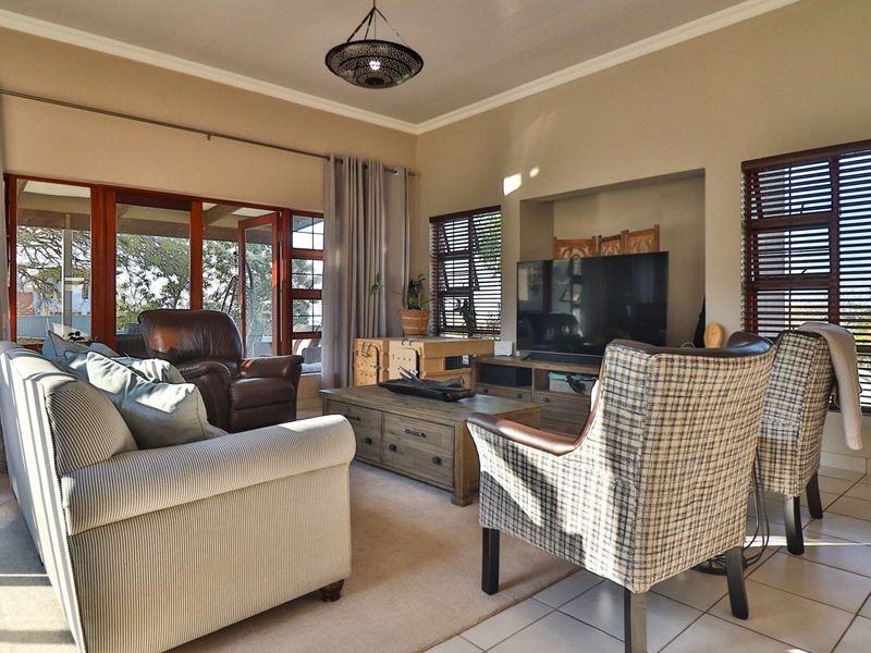A comfortable living room featuring tiled floors, a recessed media wall, and large sliding glass doors that provide access to the outdoor area.