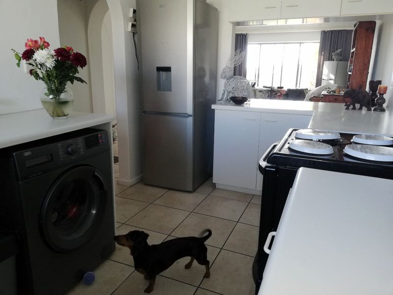 A functional kitchen featuring white cabinetry, tiled flooring, and a built-in electric stove, with an open layout connecting to the living area.