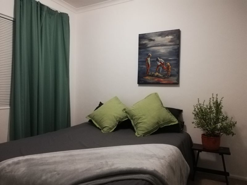 A standard bedroom featuring neutral walls, window blinds, and curtain tracks, providing a functional and comfortable sleeping space.