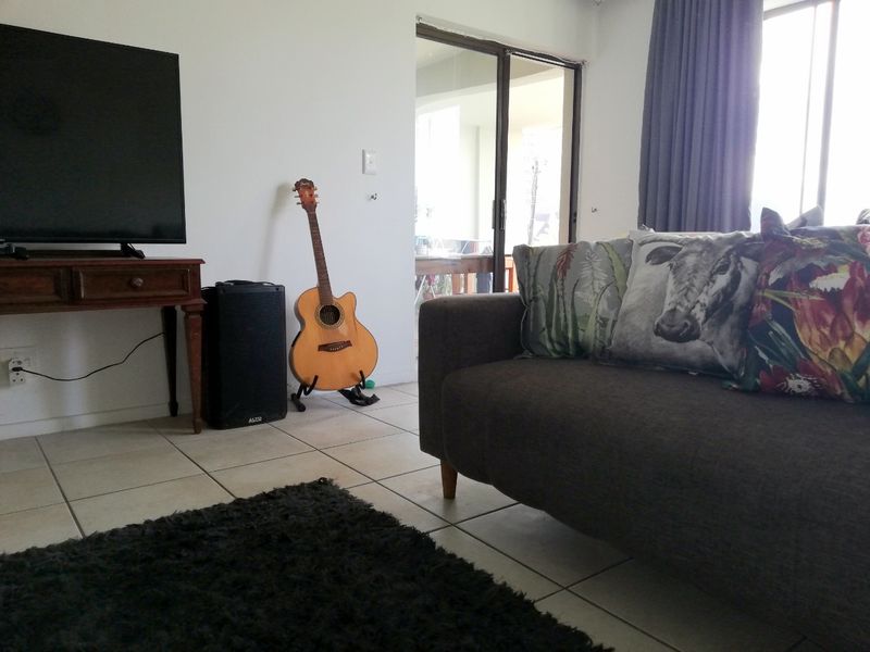 A living room area featuring tiled flooring and a sliding glass door leading to an outdoor space.