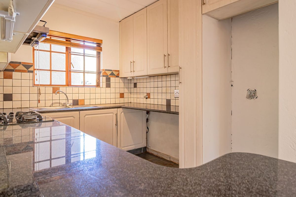 A dated kitchen featuring granite countertops, built-in cabinetry, and a gas hob, currently requiring minor repairs and cosmetic updates to modernize the space.