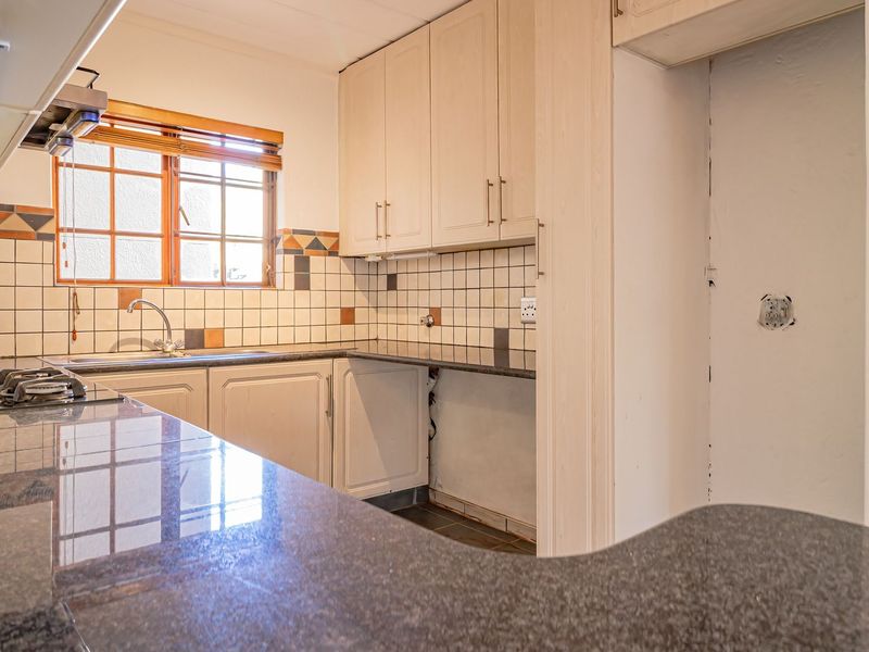 A dated kitchen featuring granite countertops, built-in cabinetry, and a gas hob, currently requiring minor repairs and cosmetic updates to modernize the space.