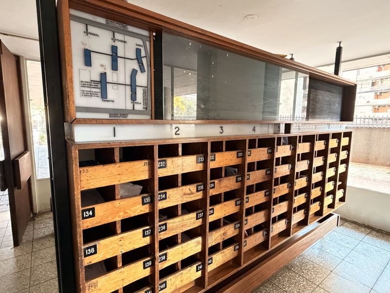 A communal building entrance area featuring a large, built-in wooden mailbox unit and a building directory map.