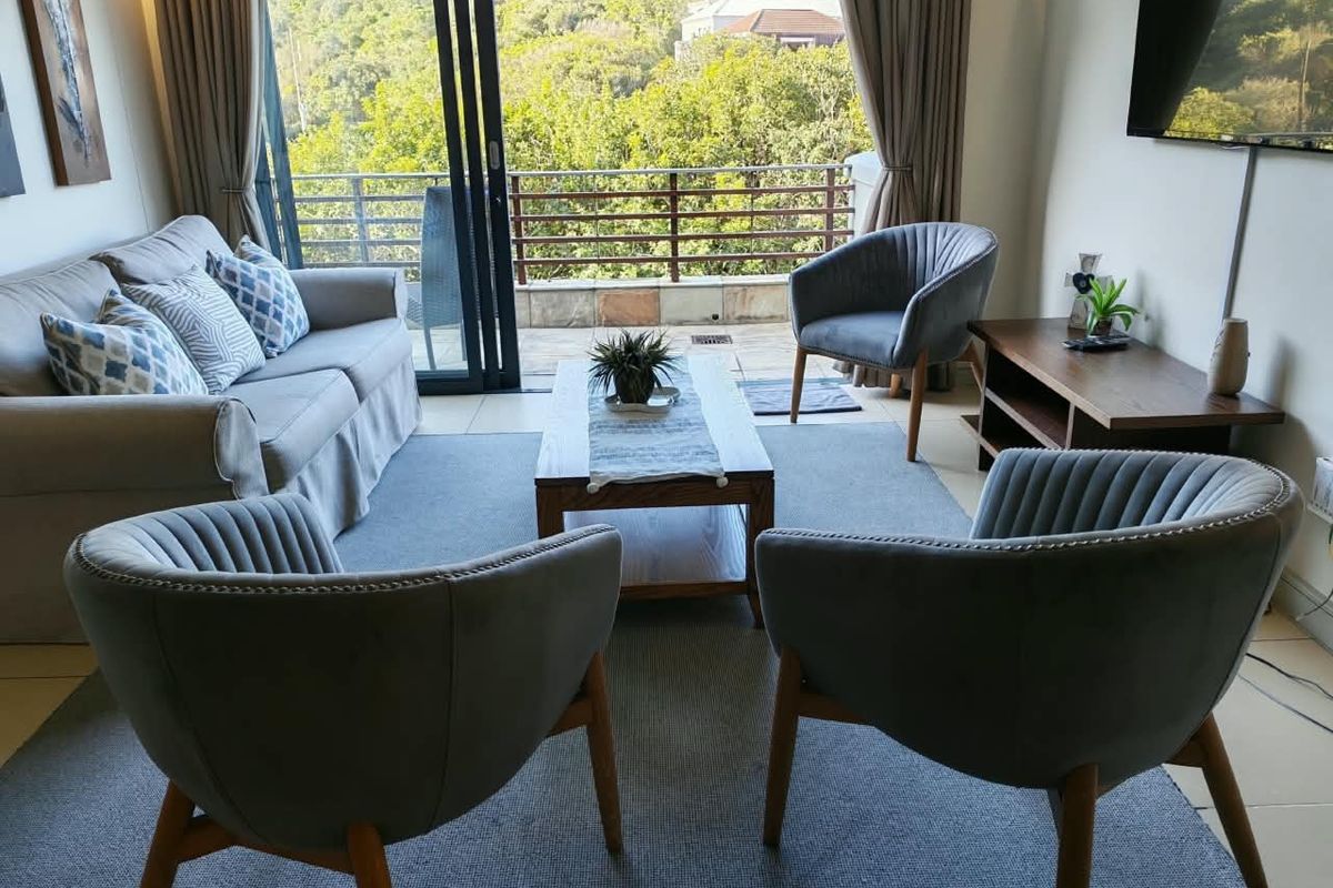 A well-maintained living room featuring tiled flooring and large sliding glass doors that open onto a balcony with scenic views.