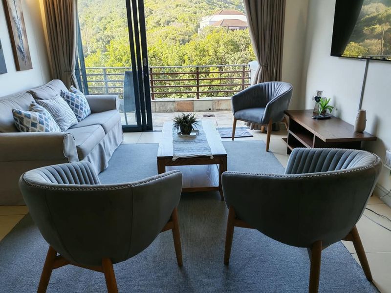 A well-maintained living room featuring tiled flooring and large sliding glass doors that open onto a balcony with scenic views.