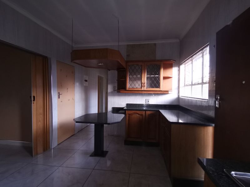 A functional kitchen featuring built-in wooden cabinetry, granite countertops, a breakfast bar, and tiled flooring, offering a solid foundation for modern updates.