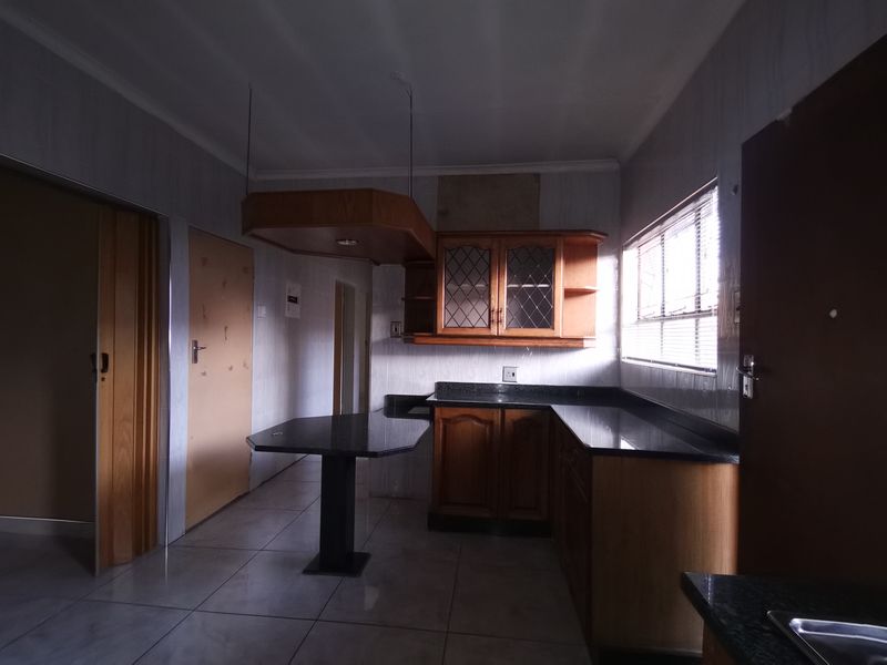 A dated kitchen featuring wooden cabinetry, granite countertops, and a built-in breakfast nook, offering significant potential for a modern renovation.