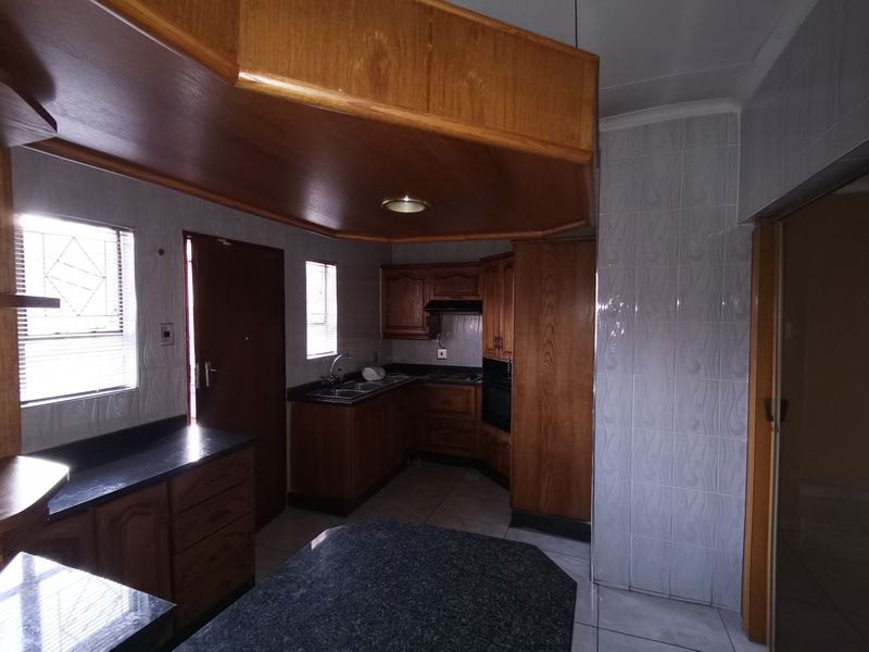 A functional kitchen featuring built-in wooden cabinetry, granite countertops, a double sink, and a built-in oven with a distinctive wooden bulkhead ceiling.