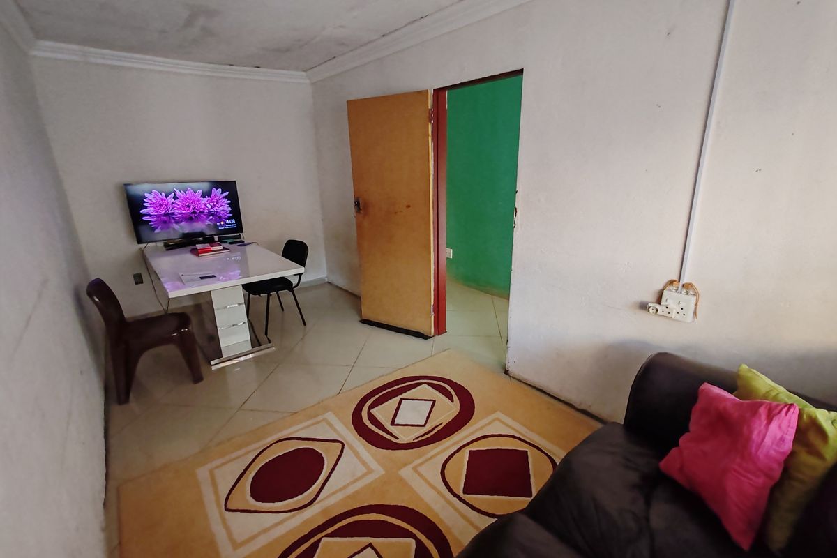 A living room featuring tiled flooring and cove cornicing, requiring cosmetic updates to the walls and ceiling to improve the overall condition.