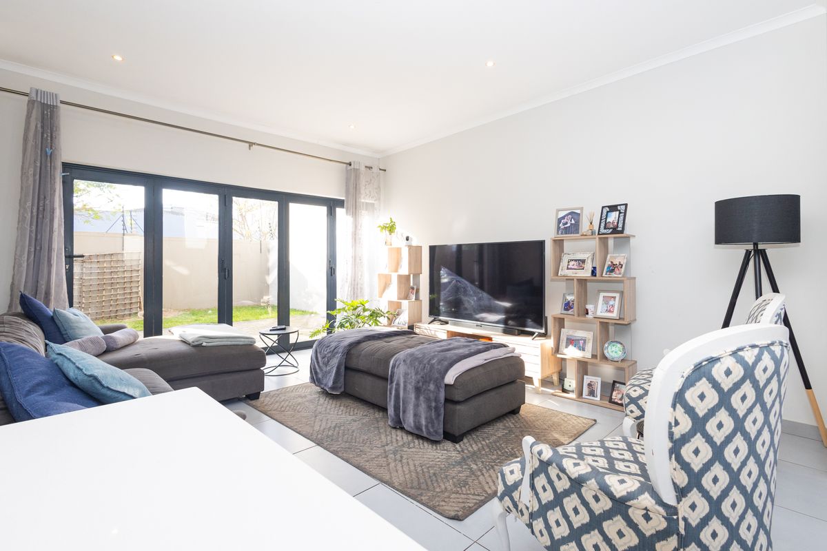 Bright and modern living room featuring large aluminium sliding doors that provide seamless access to the rear garden and patio area.