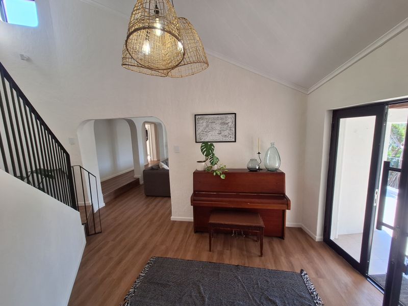 Bright entrance hall featuring vaulted ceilings, modern laminate flooring, and elegant arched doorways leading to the living areas.