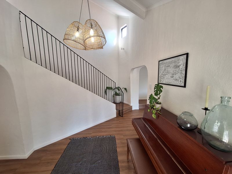 Welcoming entrance hall featuring a staircase with a modern metal balustrade, vaulted ceilings, and arched architectural details leading to adjacent living spaces.
