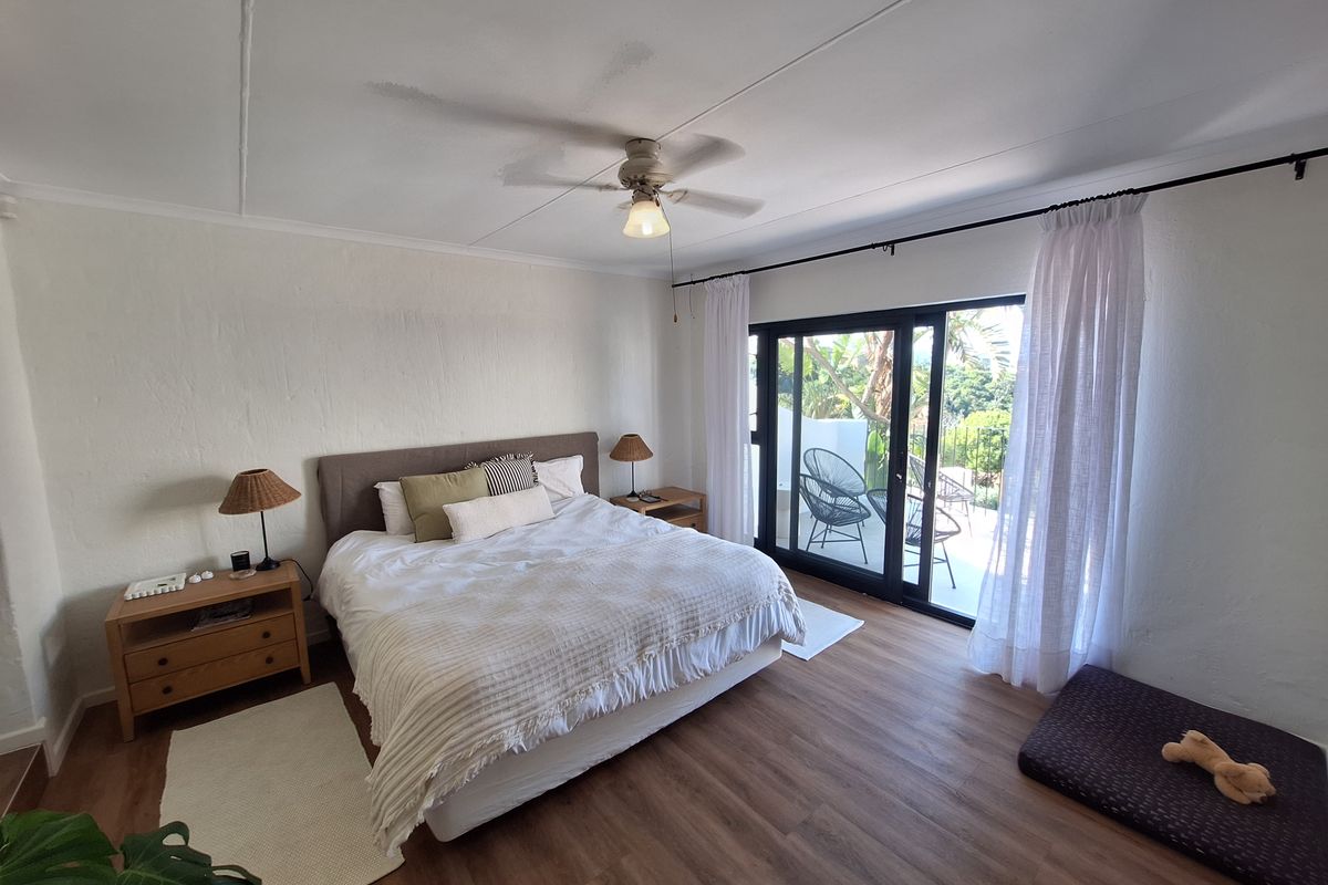 Spacious bedroom featuring laminate flooring, a ceiling fan, and large sliding glass doors providing access to an outdoor area.
